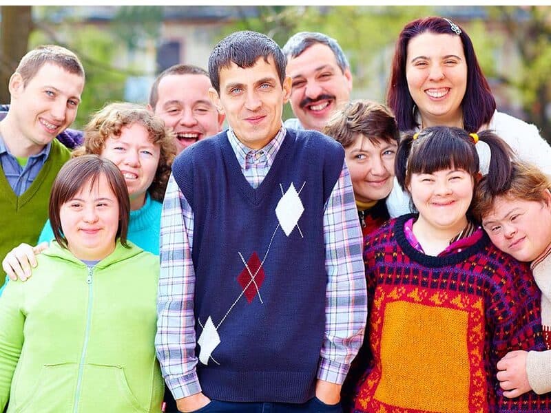Group of individuals with intellectual and developmental disabilities smiling together outdoors